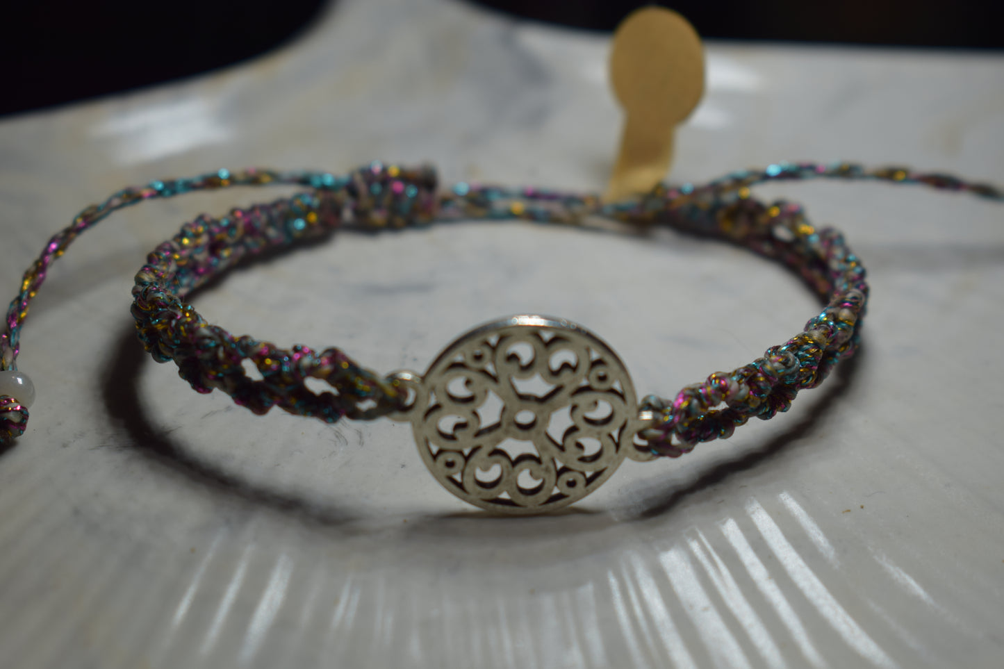 Bracelet en macramé multicolore avec un ornement en métal argenté ajouré